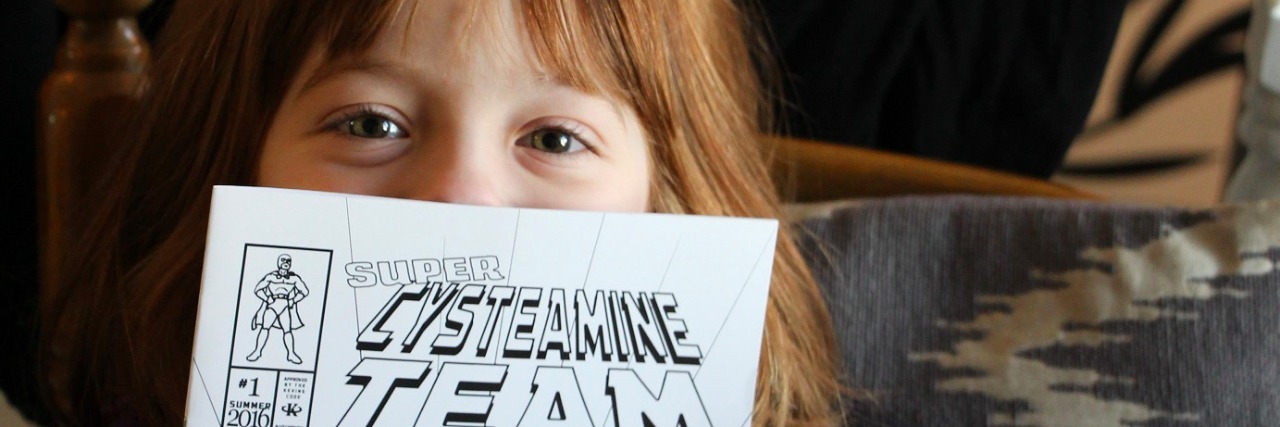 Making Cystinosis Cool With Comic Books little girl holding up comic book