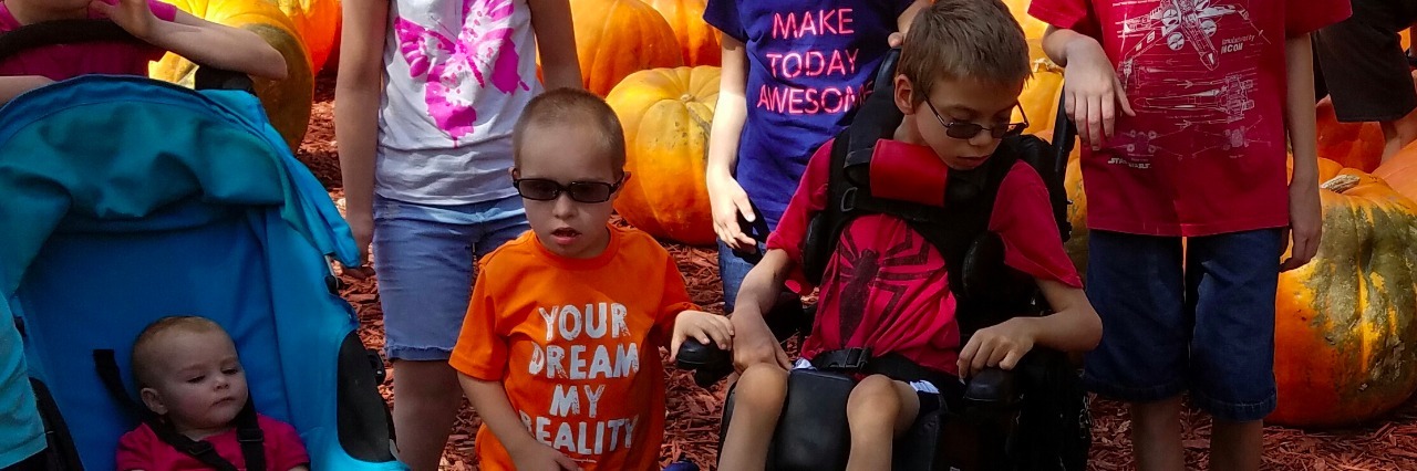 a group of children some with special needs in a pumpkin patch with a service dog