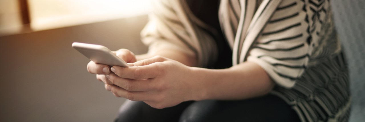 Reasons Why I Share Stories About Chronic Illness woman holding a smartphone