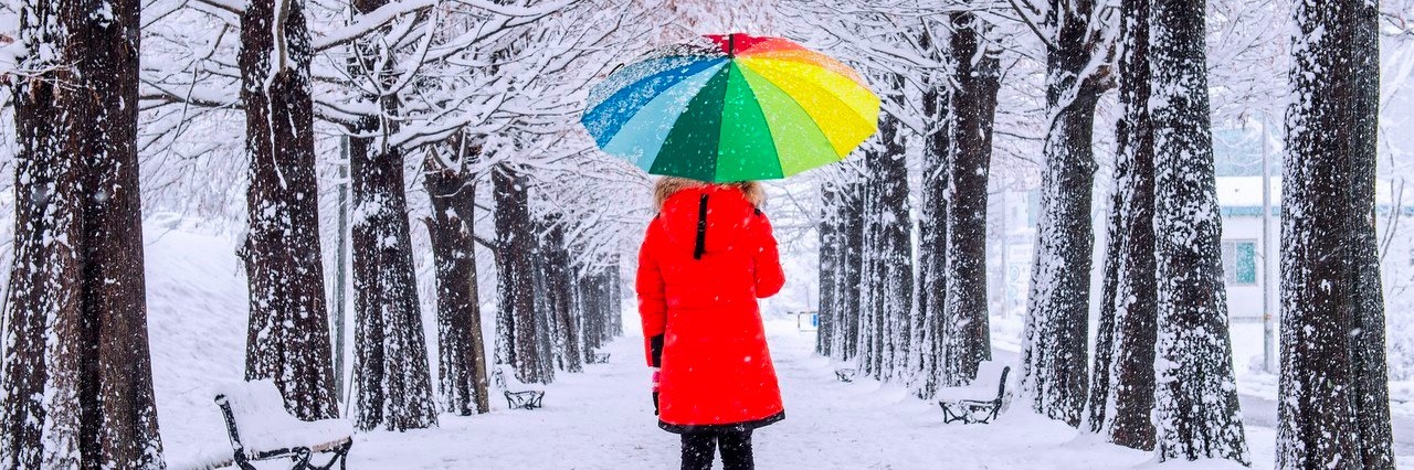 woman with colorful umbrella walking in the snow