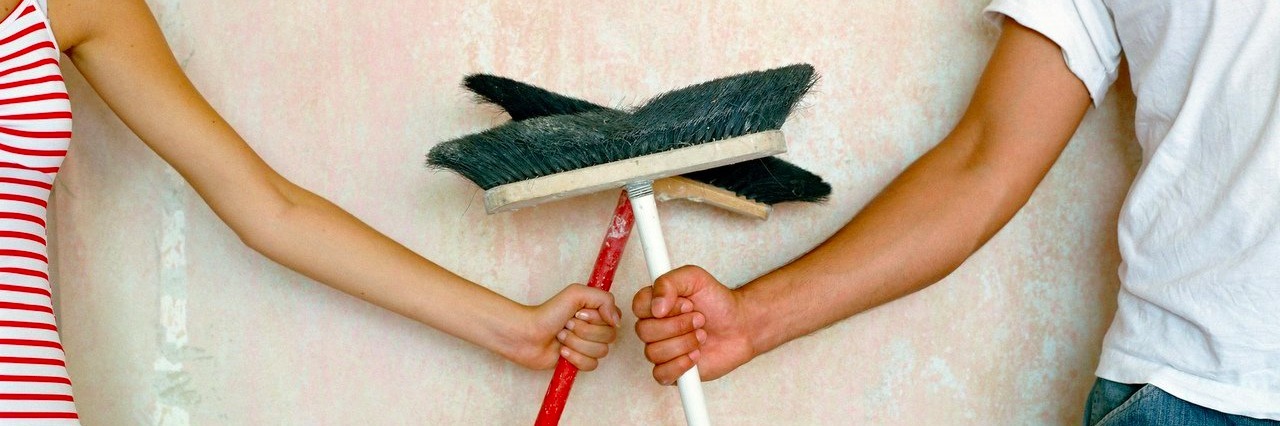 Couple holding brooms