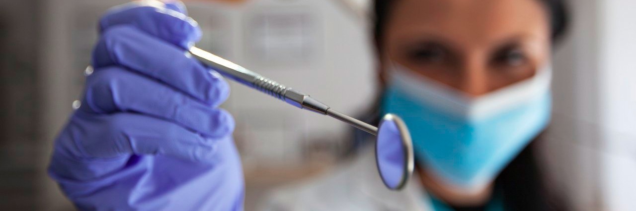 Tips for Visiting the Dentist When You Have Fibromyalgia dentist holding dental mirror instrument