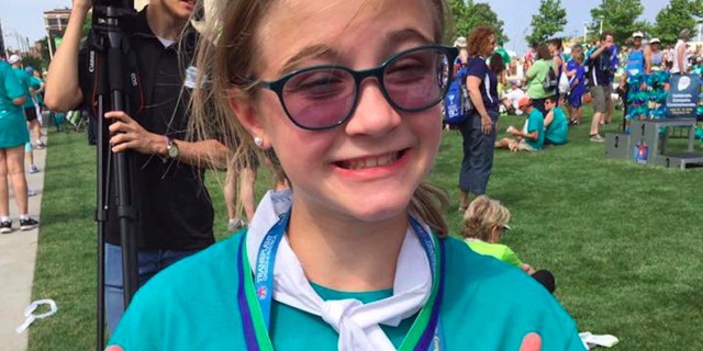 girl wearing a medal and giving a thumbs up