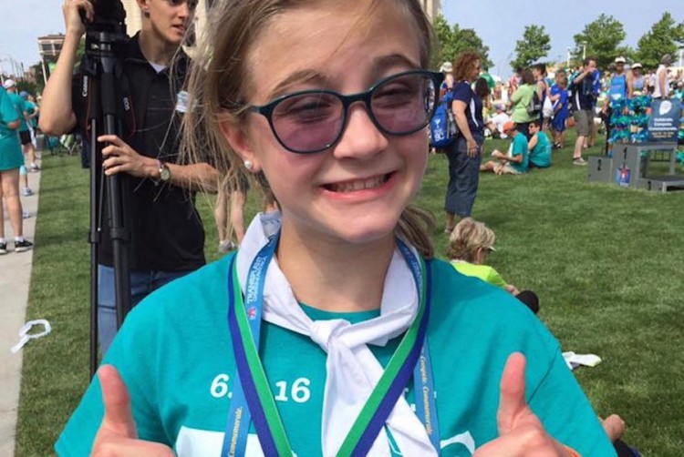 girl wearing a medal and giving a thumbs up