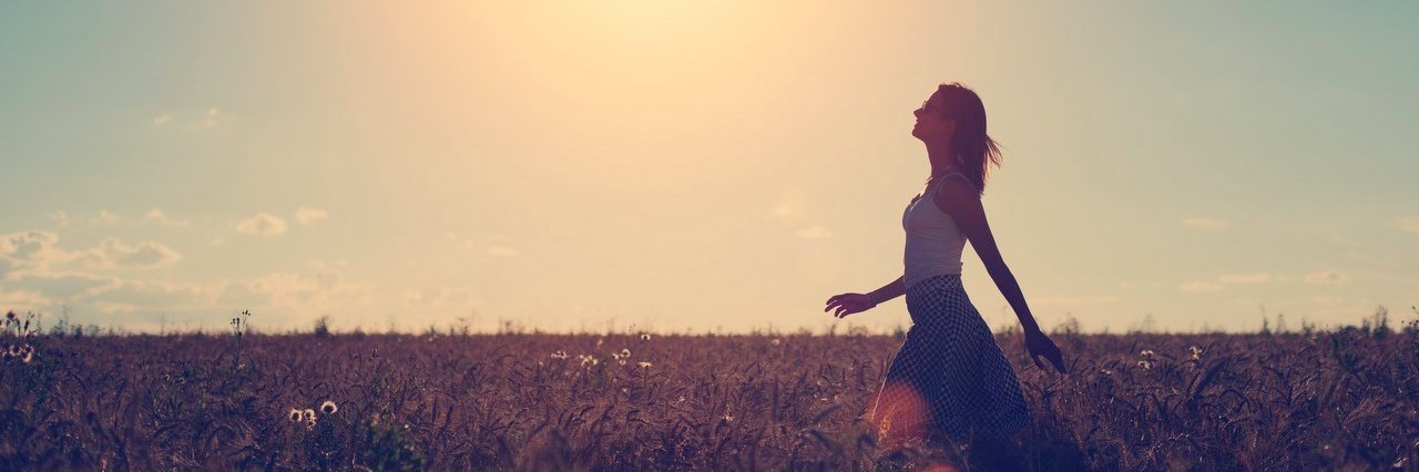 Woman Finds Positives About Her Illnesses Through a Quote woman walking in a field in the evening