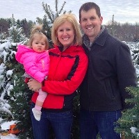 family posing with Christmas trees