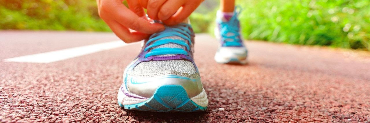 Woman With Chronic Illnesses Determined to Run a Half-Marathon young woman tying shoelaces on her running shoes