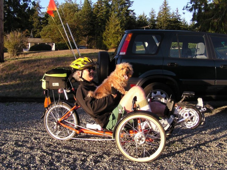 man sitting on recumbent bike with dog on lap
