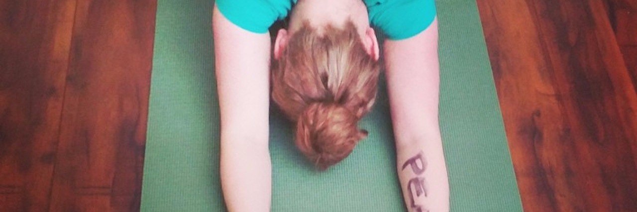 Finding Peace When Battling Autoimmune Disorder woman in blue shirt doing yoga pose with 'peace' written on her arm