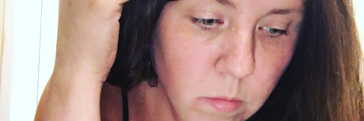 My Experience With Happiness Giving Me Anxiety A woman looking down, with one hand on the side of her head