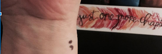 A woman's wrist showing her semicolon tattoo