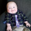 Jude, a little boy with Down syndrome wearing a plaid shirt and tie..