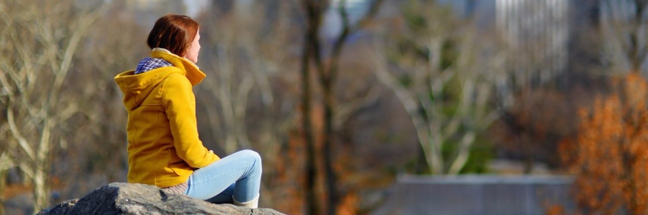 Young woman sitting on a rock in Central Park in New York City.