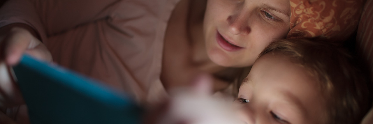 6 Things Every Parent With Anxiety Should Remember Mother and little son watching video or playing on touchpad lying in bed at night