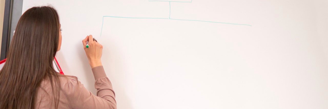 Teacher With Chronic Fatigue Syndrome Stops Pushing Herself teacher drawing diagram on the whiteboard