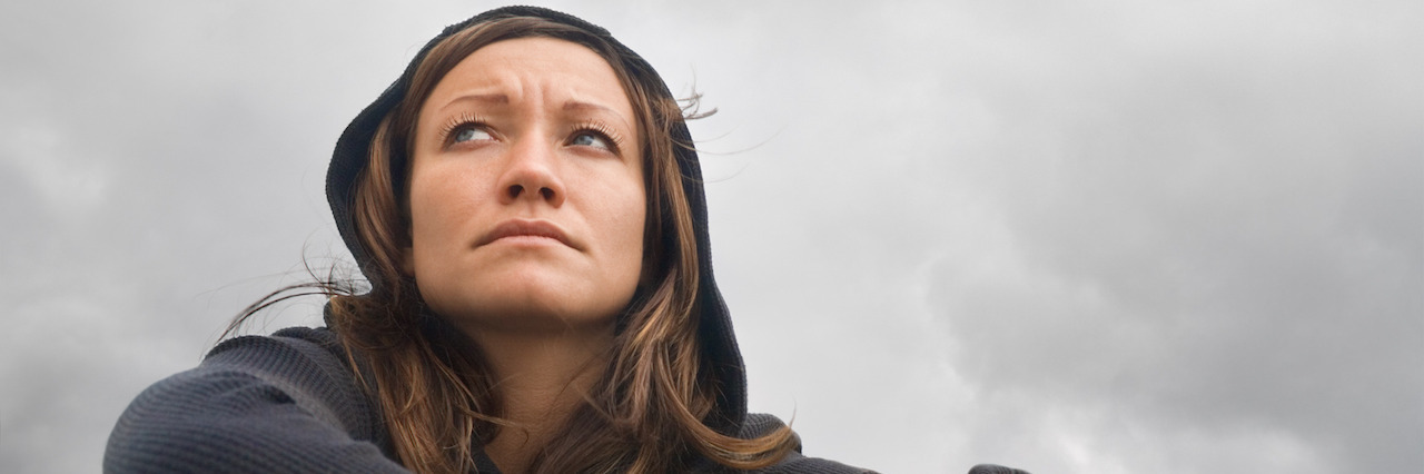 Girl sitting and contemplating on a background of a cloudy sky