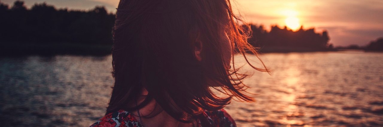 Things People Need to Understand About Chronic Pain young woman is looking at sunset over the river