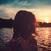 young woman is looking at sunset over the river