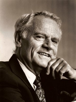 A black and white photo of a man with his hand to his chin