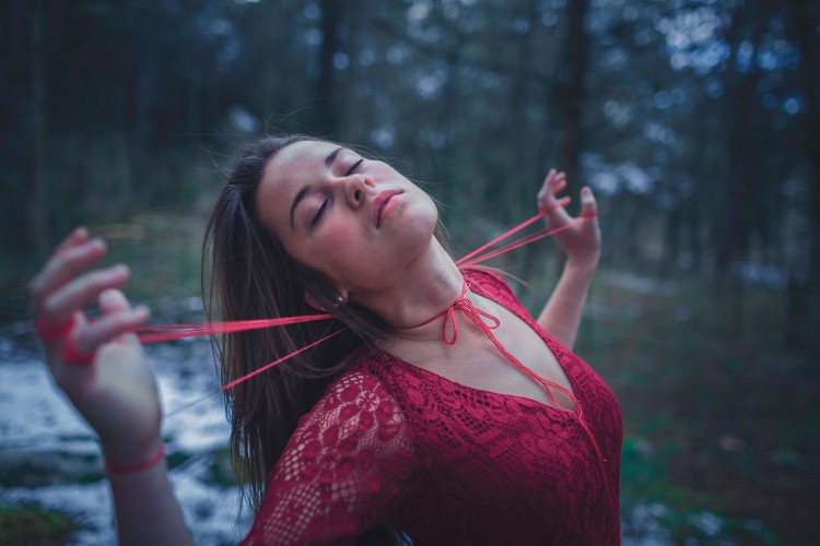 woman holding red string wrapped around her neck and fingers