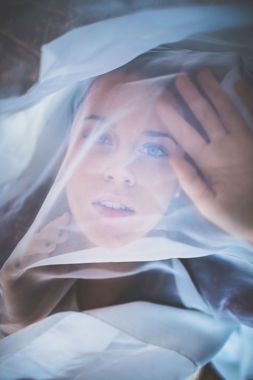 woman looking through sheer white fabric