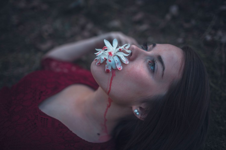 girl laying back with plant dripping with red paint on mouth