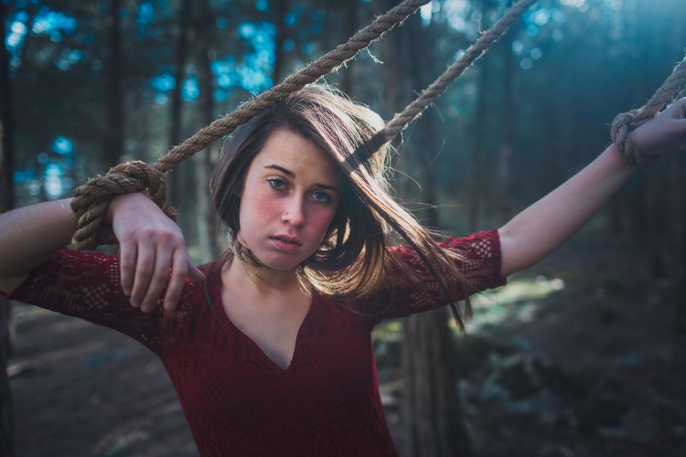 woman standing with ropes wrapped around her neck and hands