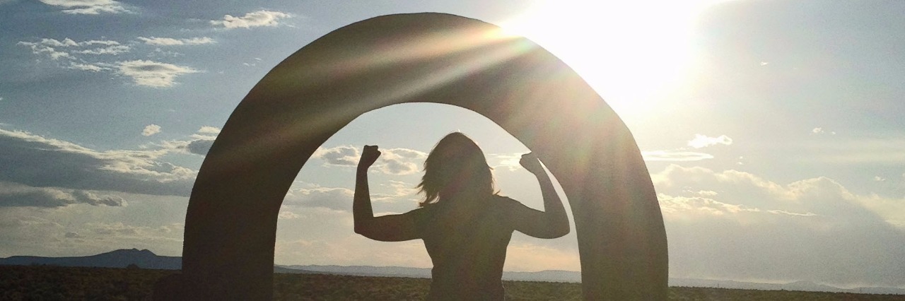 woman standing under arch at sunset