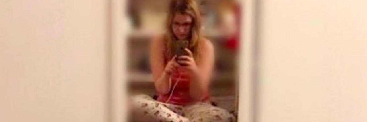 Woman With Hypothyroidism Feels Like a Burden to Others young woman takes photo of herself in a mirror