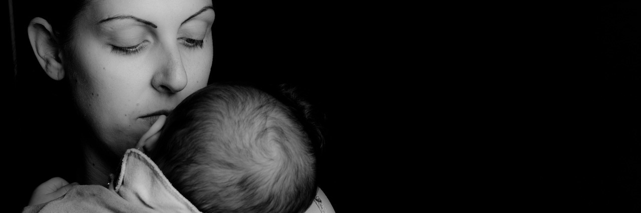 How I Learned to Bond With My Baby in Postpartum Psychosis A mom holding her newborn in her arms in a black and white image