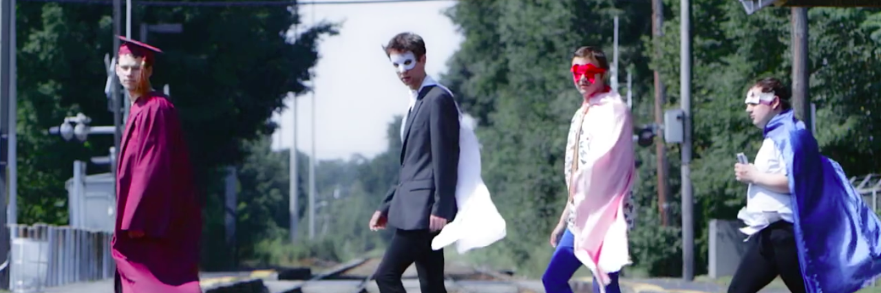Members of Aspergers Are Us dressed in costumes walking along a railroad track