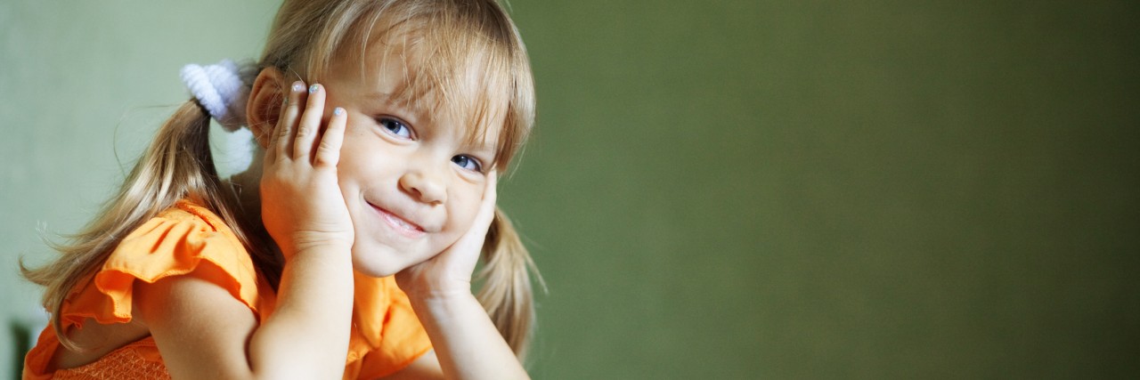 Autistic Adult Answers How to Explain an Autism Diagnosis to a Child Lovely child sitting at table looking at camera and smiles