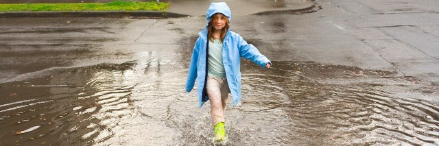 young girl playing in a rain puddle