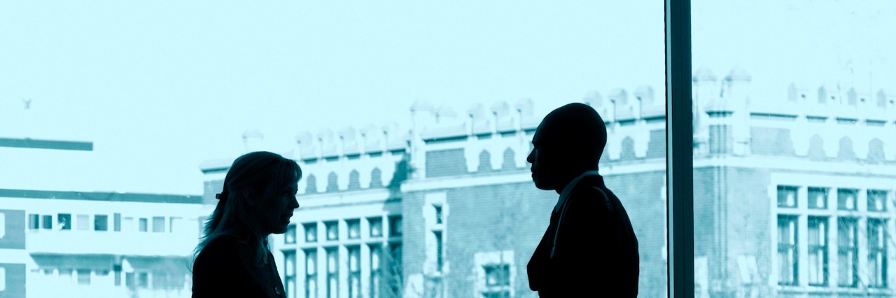 Learning a Parenting Lesson After Talking About My Son's Autism Two business colleagues standing in front a large window, talking