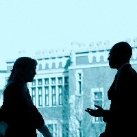 Two business colleagues standing in front a large window, talking