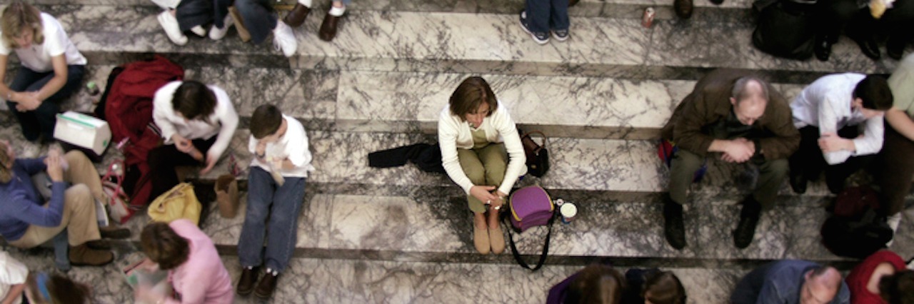 woman sitting alone in the middle of a crowd