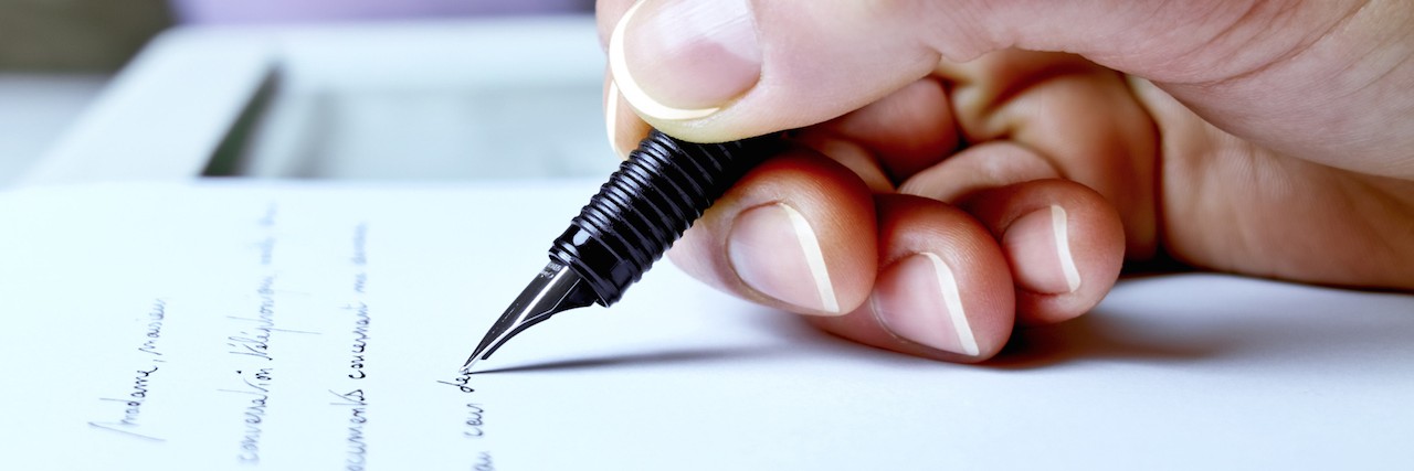 close up of a hand holding pen and writing on a piece of paper