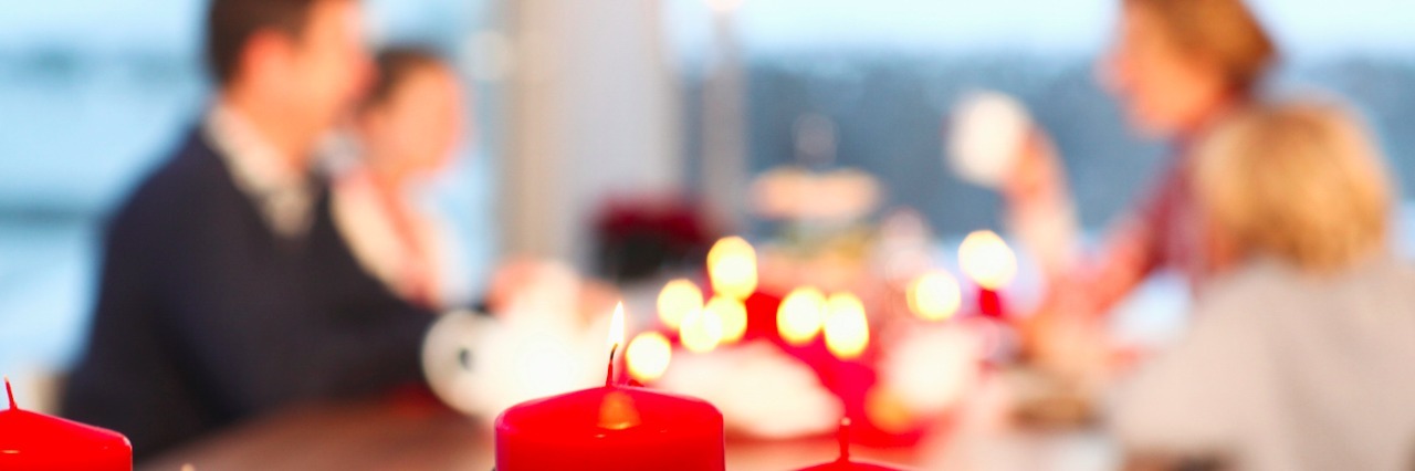 Autism: Making Holiday Activities More Enjoyable for My Child Close up of red candles with family in the background sitting at a table