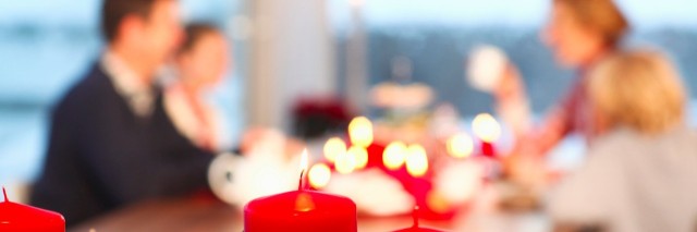 Close up of red candles with family in the background sitting at a table
