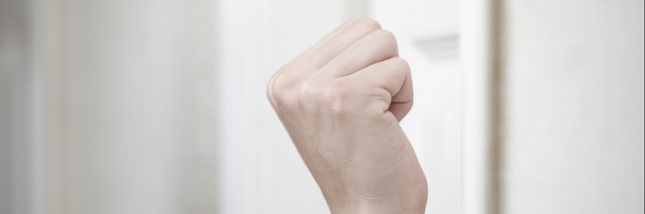 Depression, the Unwelcome Familiar Guest Human fist hovering in front of door, getting ready to knock