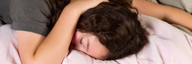 Young girl trying to wake up in the morning with hand over her head while lying in bed