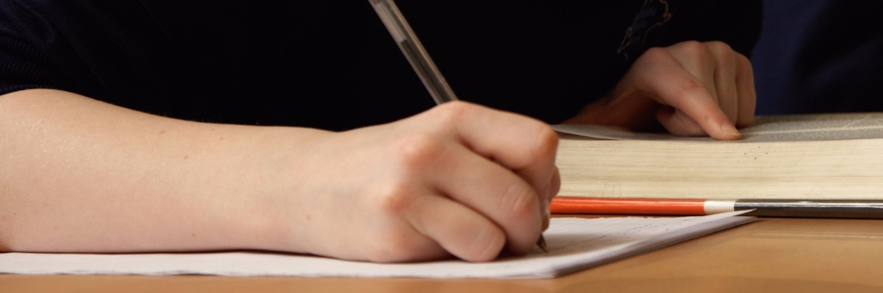 Autism: Helping My Daughter Understand We All Learn at Different Rates Student in classroom taking notes next to open book on table