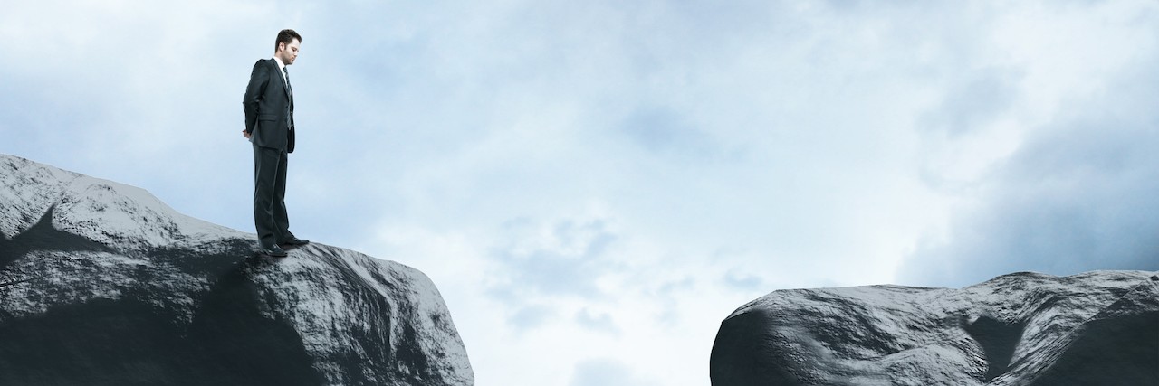 Getting Through Hards Days With Anxiety and Depression business man looking over the edge on a big rock