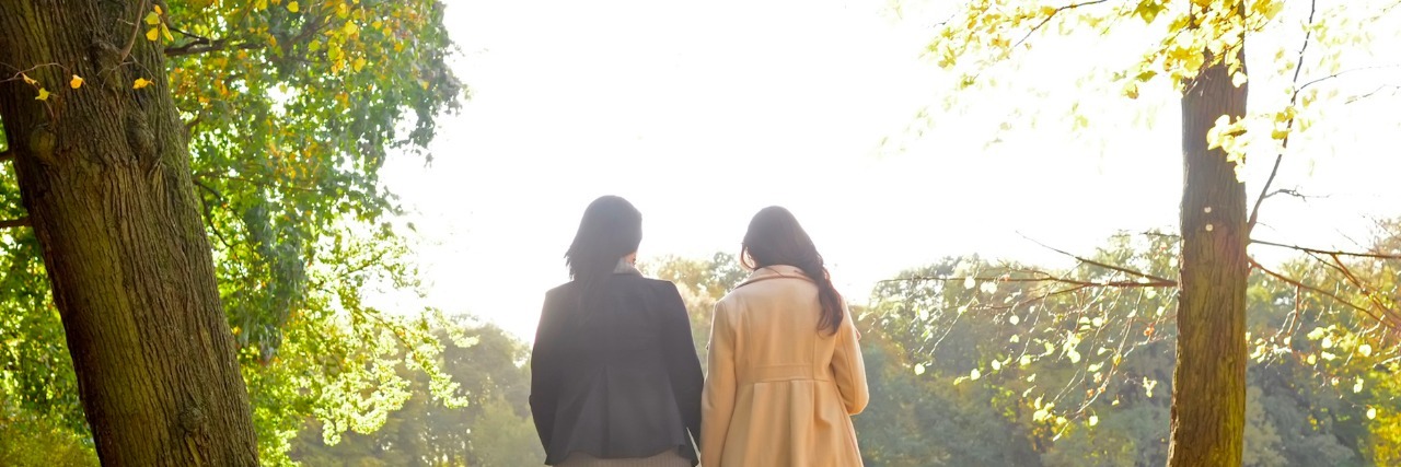 Talking to Others About My Experience With Secondary Infertility Two women walking together in a park in the fall
