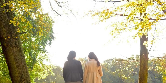 Two women walking together in a park in the fall