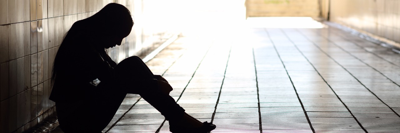 Asking for Mental Health Help as a Teenager sad teen girl sitting alone against the wall of a dark empty hallway
