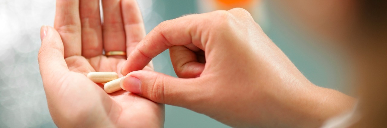 woman's hand holding two pills