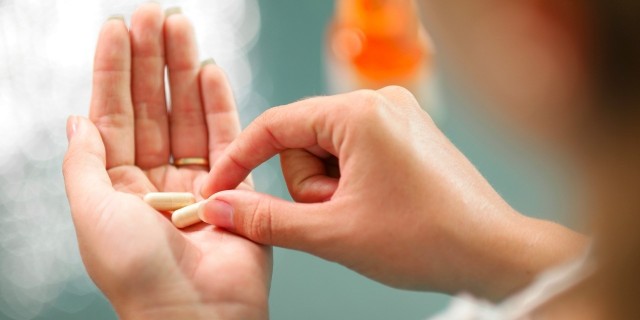 woman's hand holding two pills