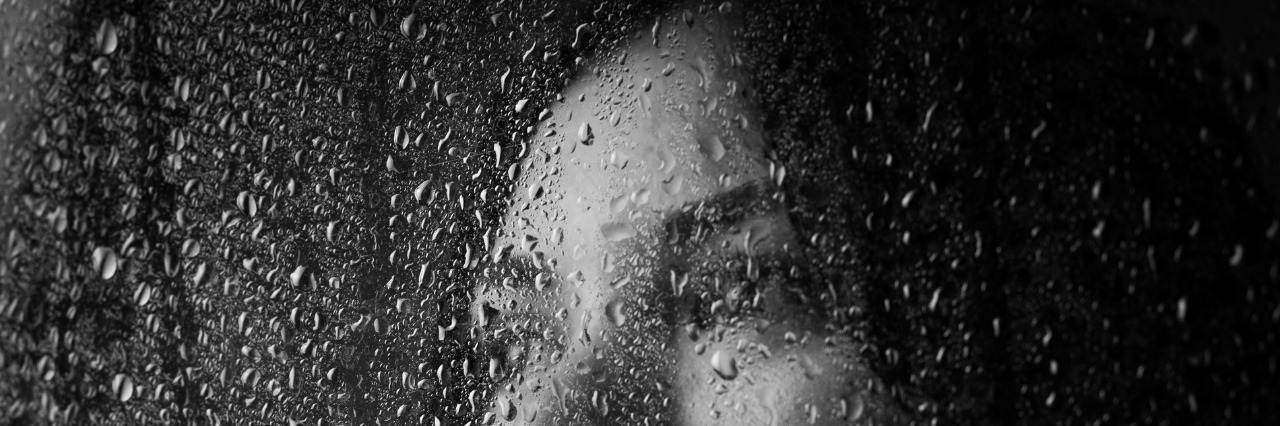 What It's Like to Lose Friends to Your Rare Illness A beautiful girl in a white t-shirt, on a black background behind the glass.