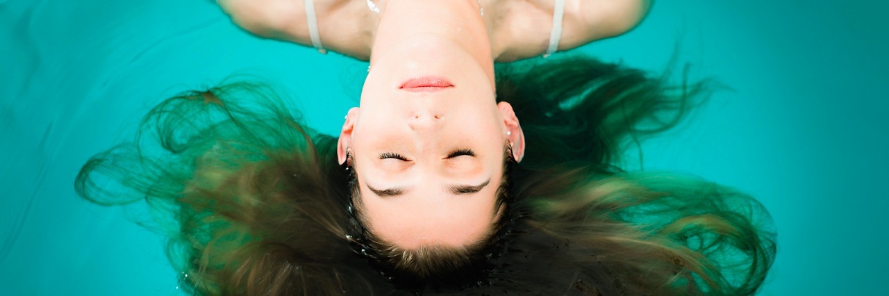 A young woman floating in a pool
